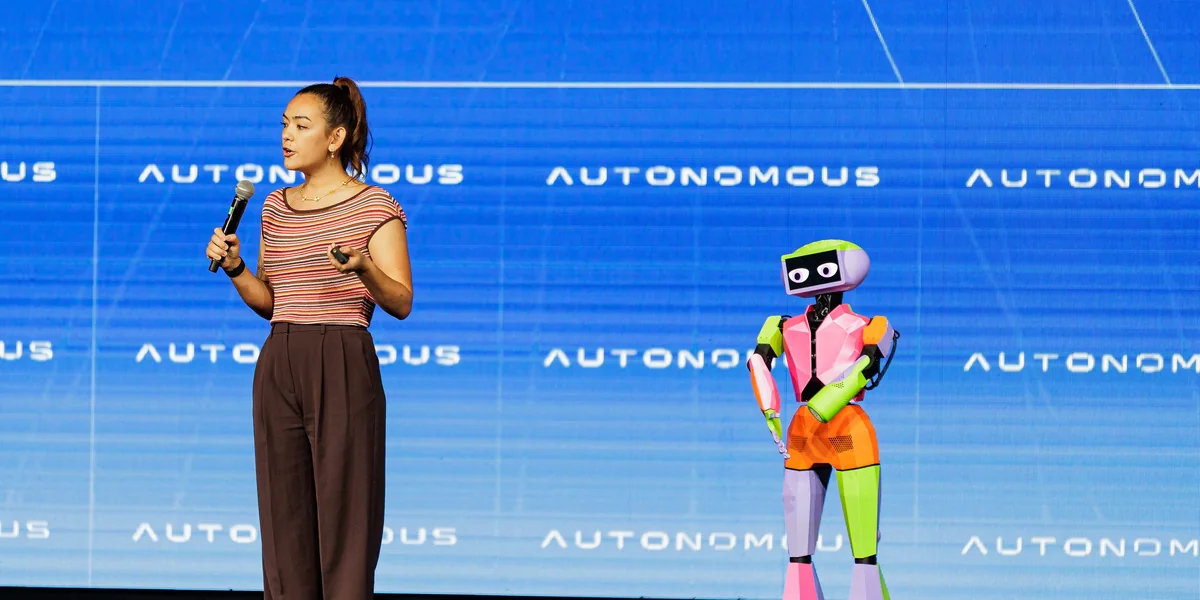 A speaker on stage beside a walking humanoid robot