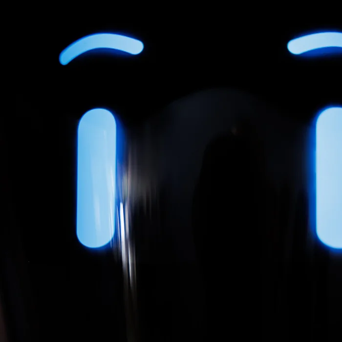 The glowing blue eyes of a robot in a darkened room
