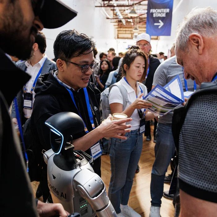 Attendees crowded around a small humanoid robot on the exhibition floor