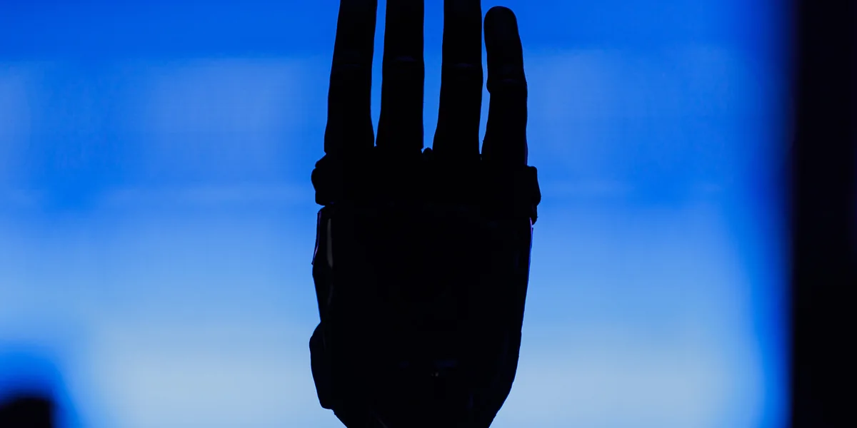 A robot hand in silhouette against a blue screen