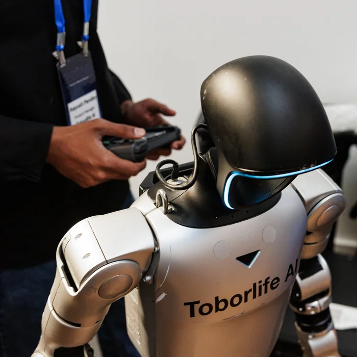 An engineer driving a humanoid robot with a handheld controller