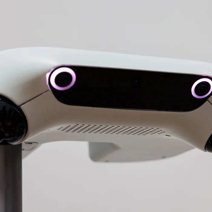 The head of a white robot, its two ring-lit camera housings glowing