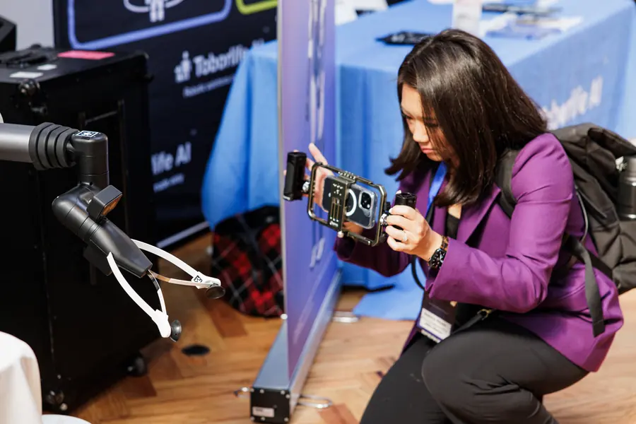 A journalist filming a robot arm on the exhibition floor