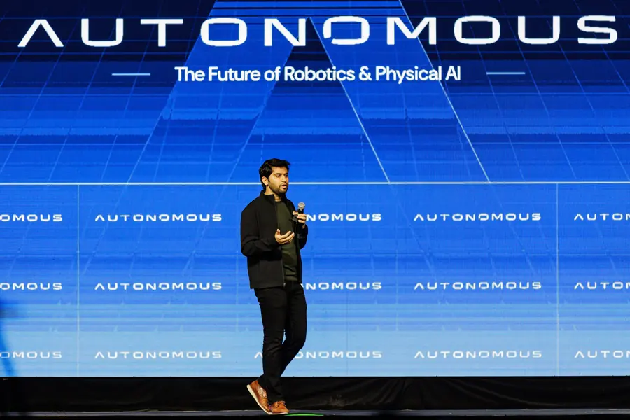 A speaker alone on stage against the full-width AUTONOMOUS screen