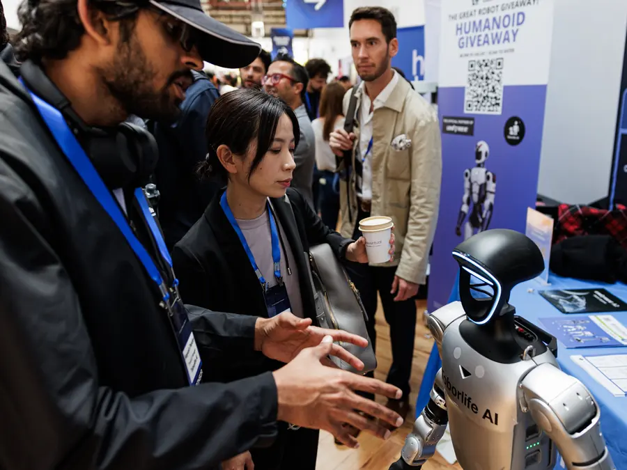 Attendees crowding a humanoid robot on the exhibition floor